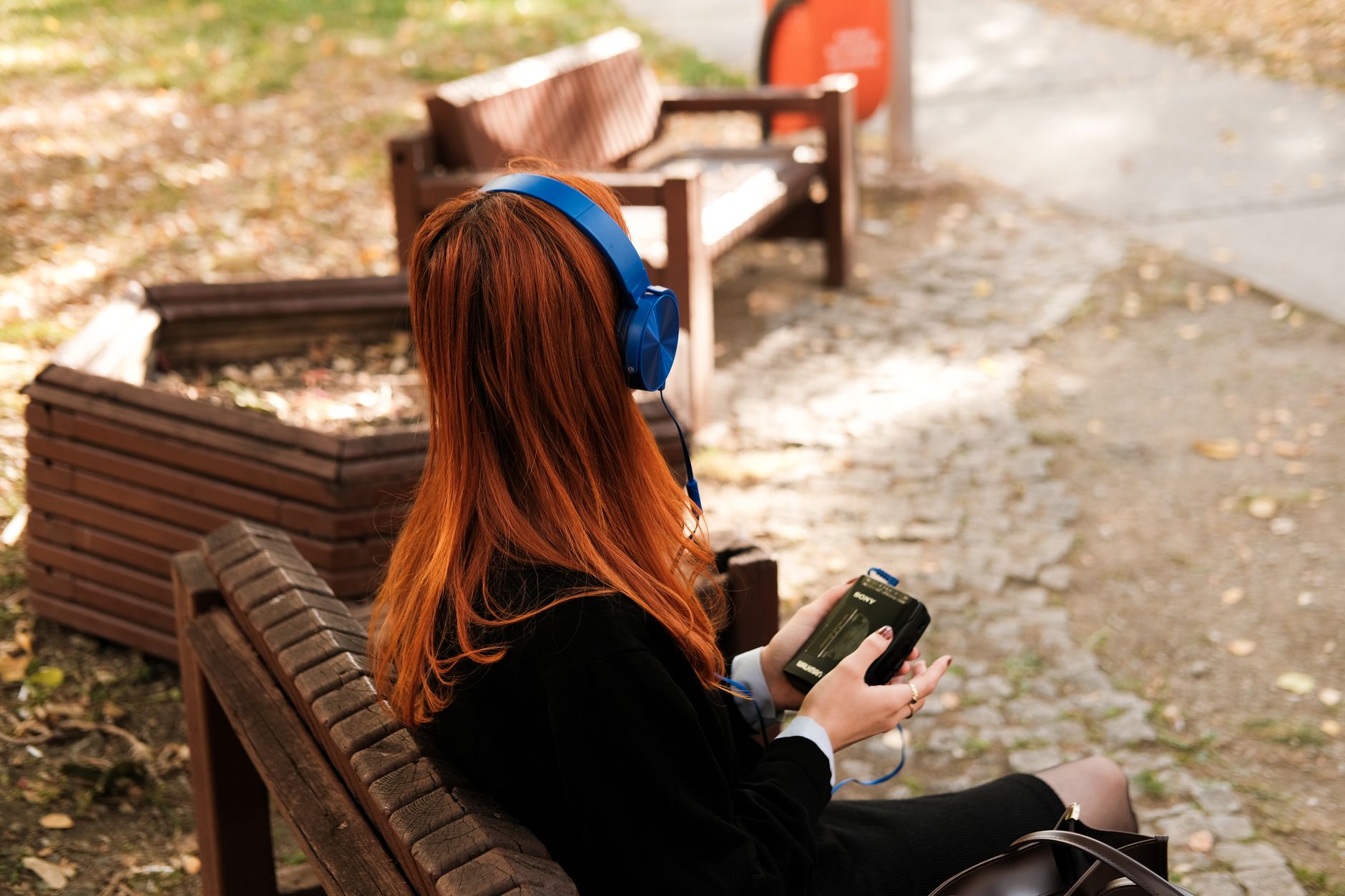 young woman with headphones sitting outdoors in autumn